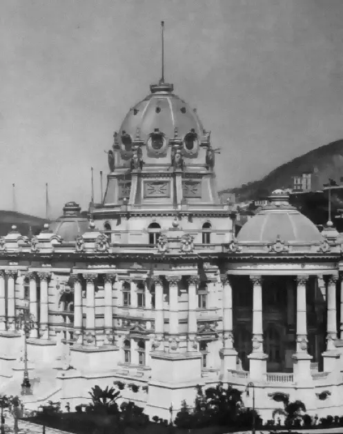 Palácio majestoso com colunas, domo ornamental e estrutura baixa, montanha ao fundo.