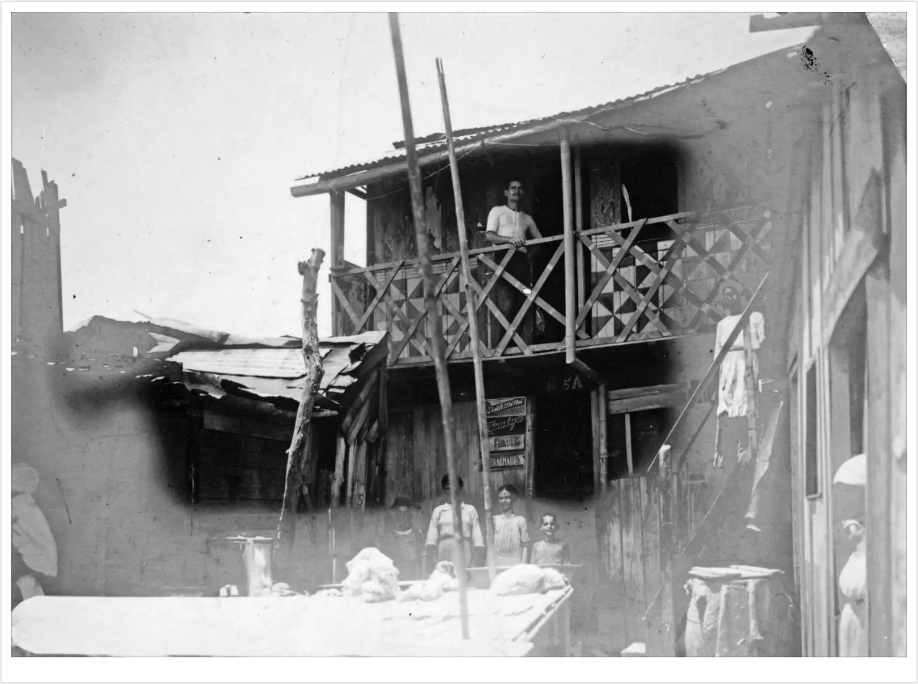 Casa antiga com varanda e loja em preto e branco.