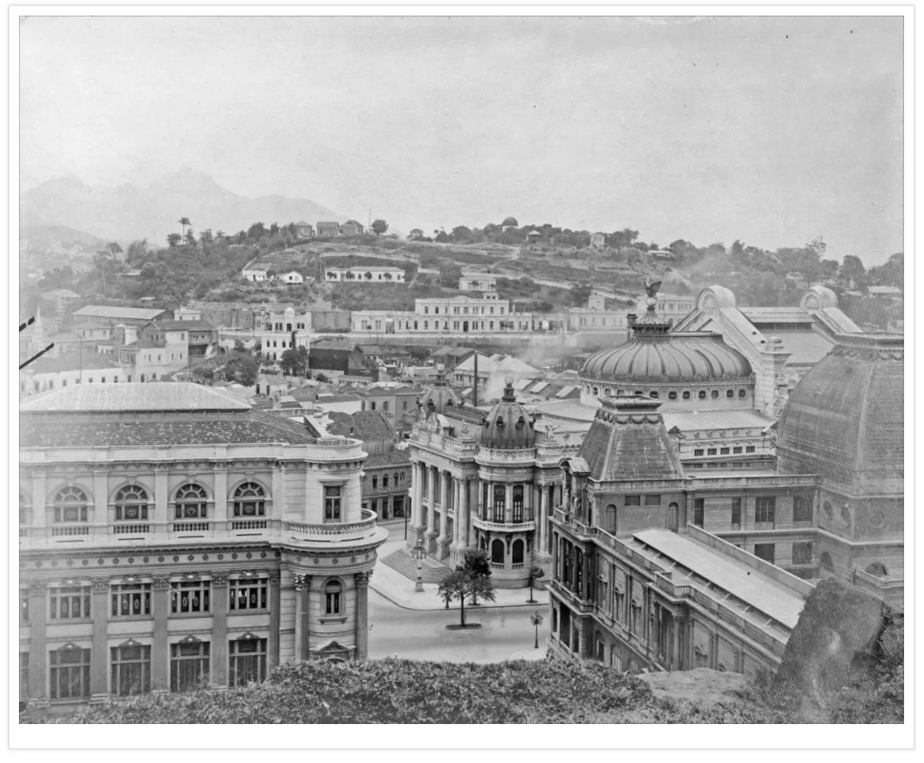 Cidade antiga com edifícios históricos e colina ao fundo.