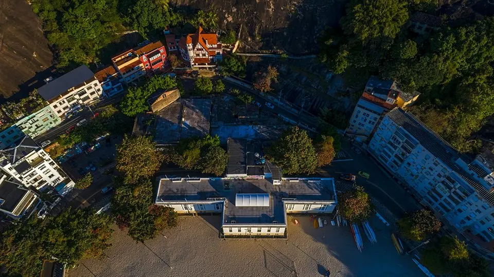 Bairro residencial com casas coloridas, prédios altos e praia arenosa.