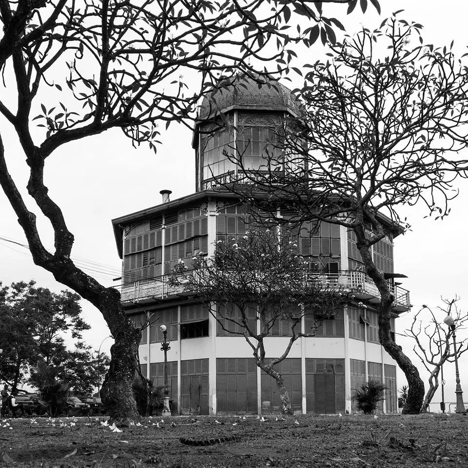 Edifício histórico com árvores e telhado redondo.