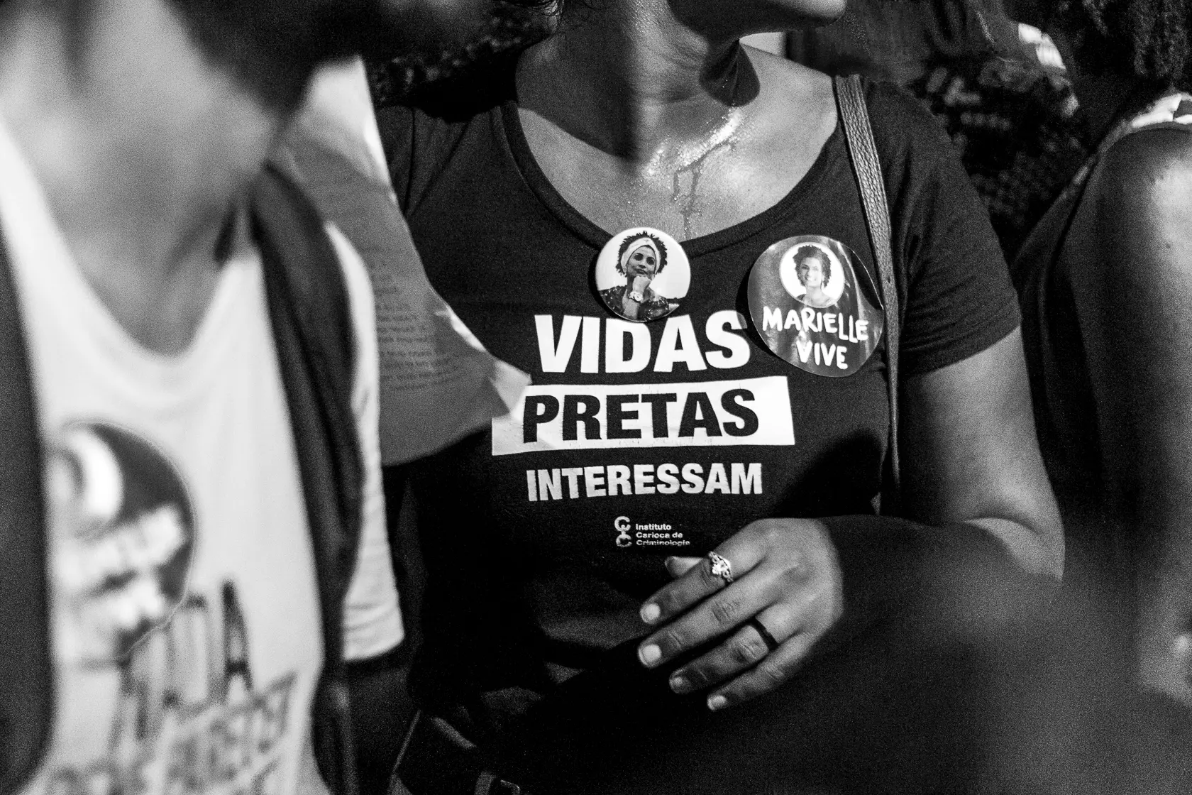 Mulher em protesto usando camiseta preta com texto "VIDAS PRETAS INTERESSAM".