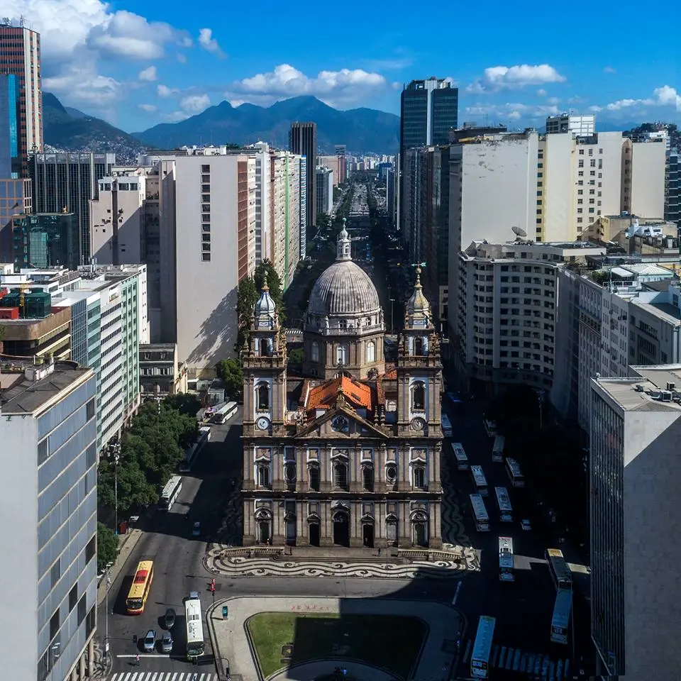 Cidade com edifícios variados e montanhas ao fundo.