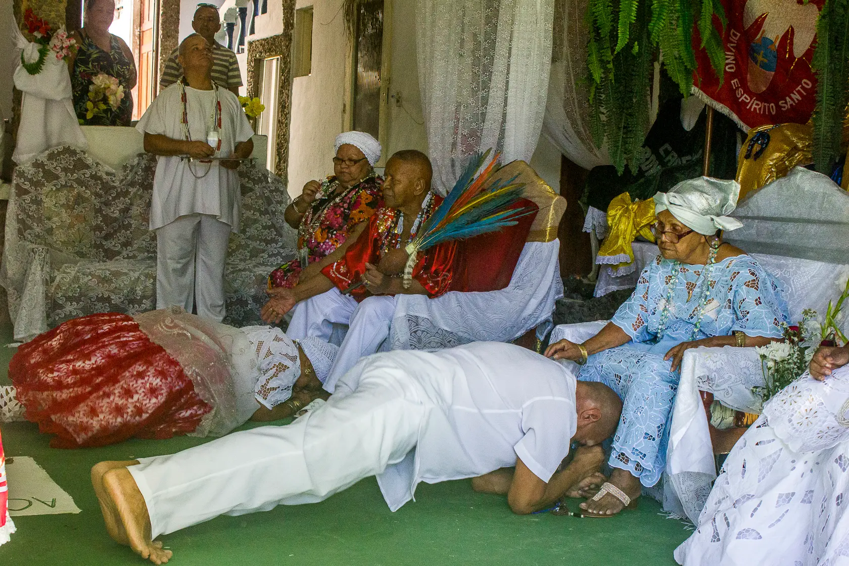 Evento cultural ou religioso com pessoas vestindo trajes tradicionais e bandeira "Divino Espírito Santo".