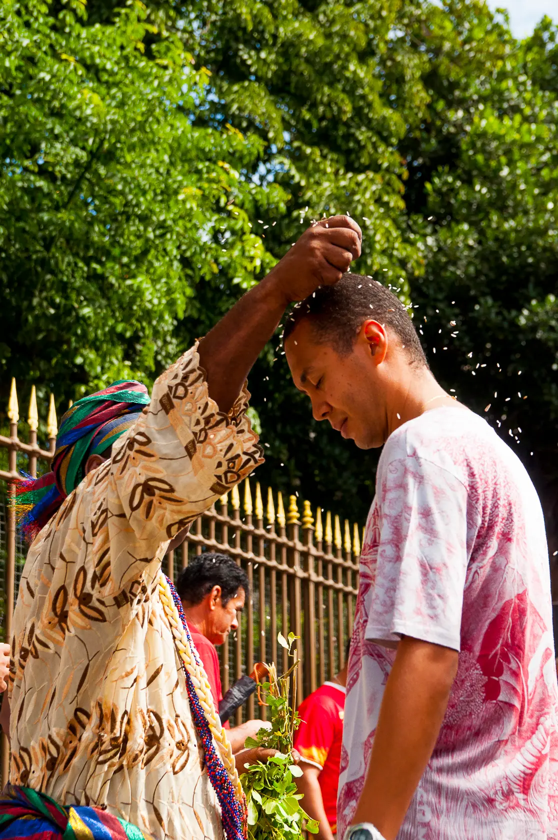 Cerimônia ao ar livre com manto dourado e lenço colorido.