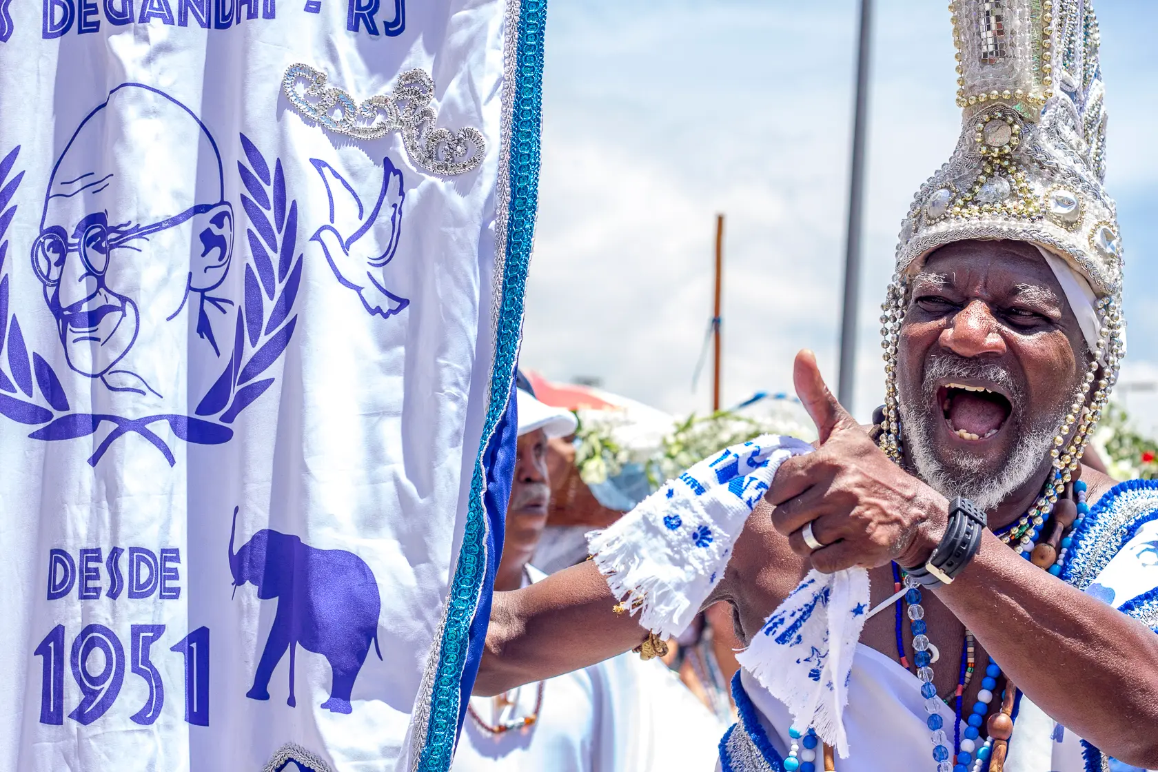 Fotografia festiva de carnaval com bandeira azul e homem sorridente.