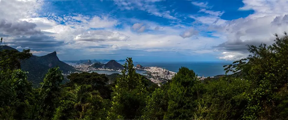 Cidade costeira com montanhas, rio e mar azul.