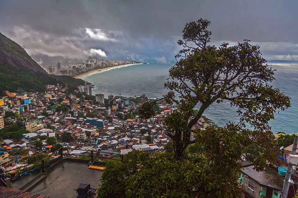Cidade costeira com montanha, edifícios coloridos e praia.