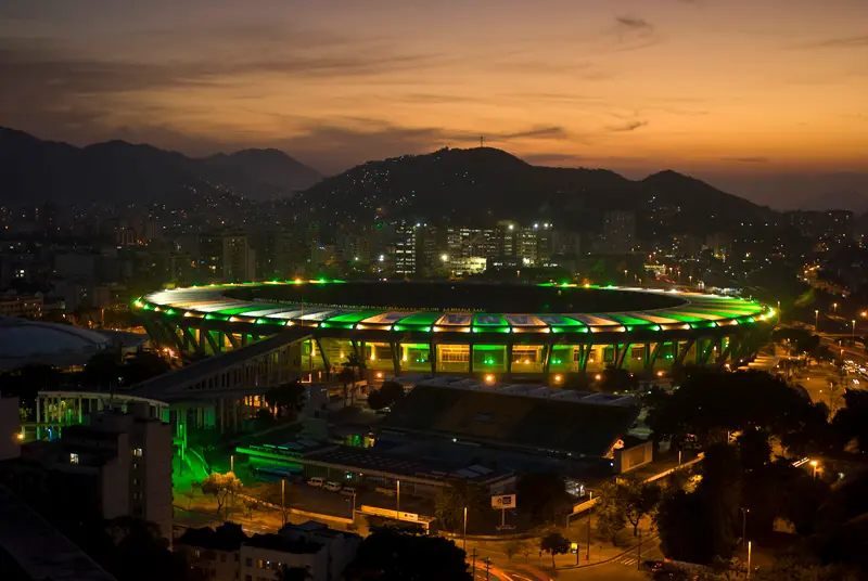 Estádio à noite com iluminação verde, pôr-do-sol.