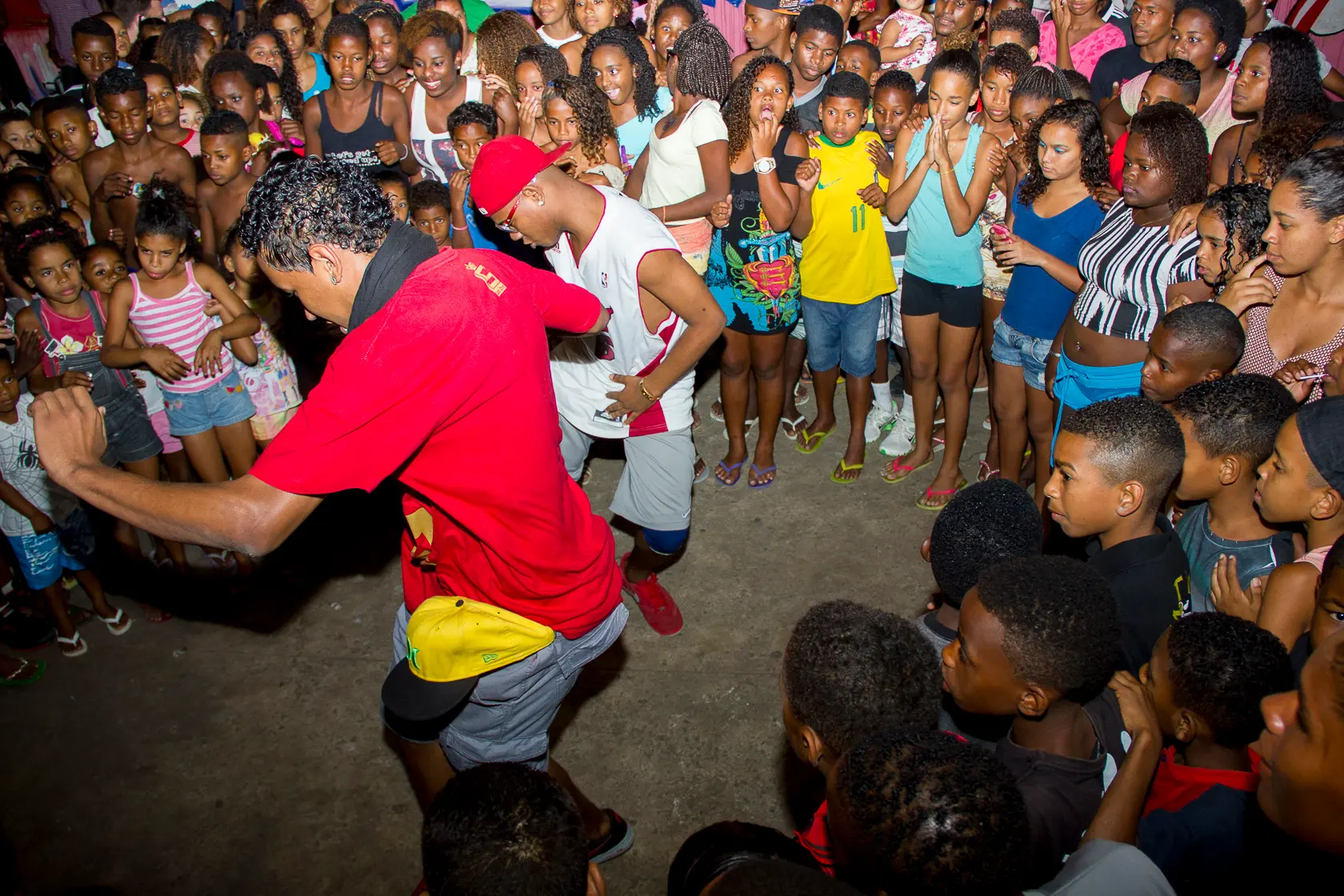 Multidão assiste a performance de dança em espaço interno.