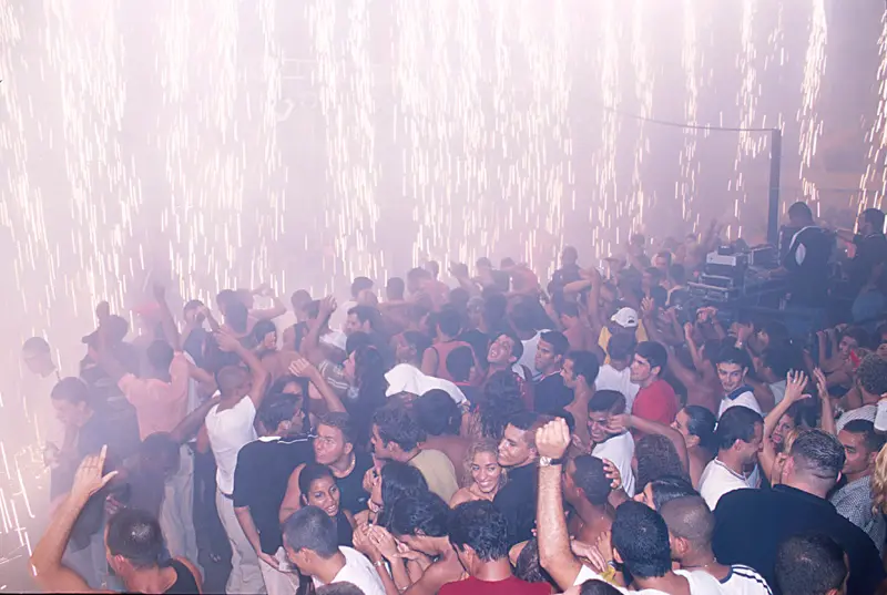 Multidão dançando em baile funk festivo em Castelo das Pedras, RJ.