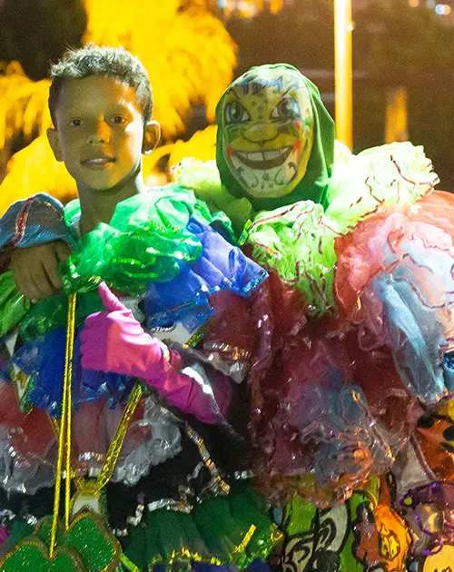 Duas pessoas em trajes coloridos de Carnaval, sorrindo e celebrando.