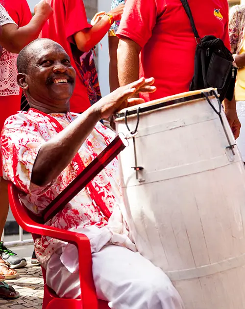 Homem tocando tambor em celebração pública.