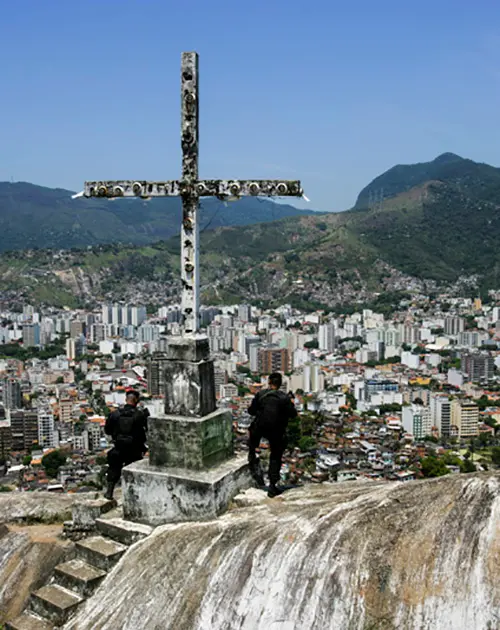Cruz monumental em ponto elevado, cidade ao fundo.