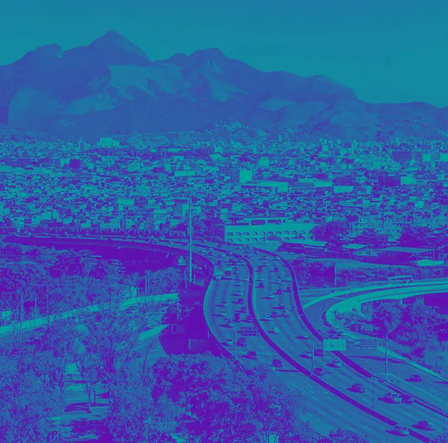 Cidade com montanhas ao fundo, área verde à esquerda, complexo viário no centro, edifícios à direita.