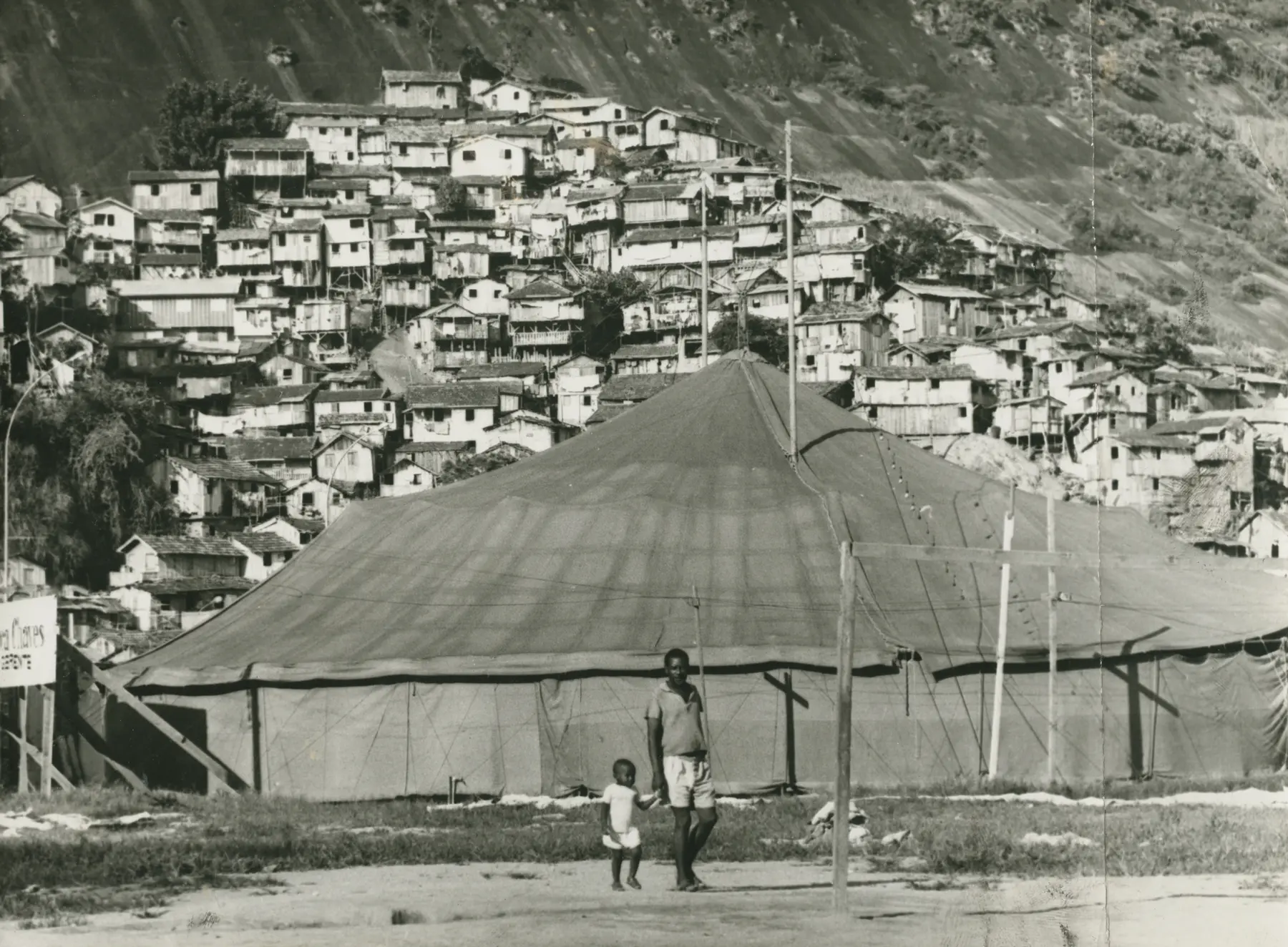 Acampamento montanhoso com tenda e casas simples.