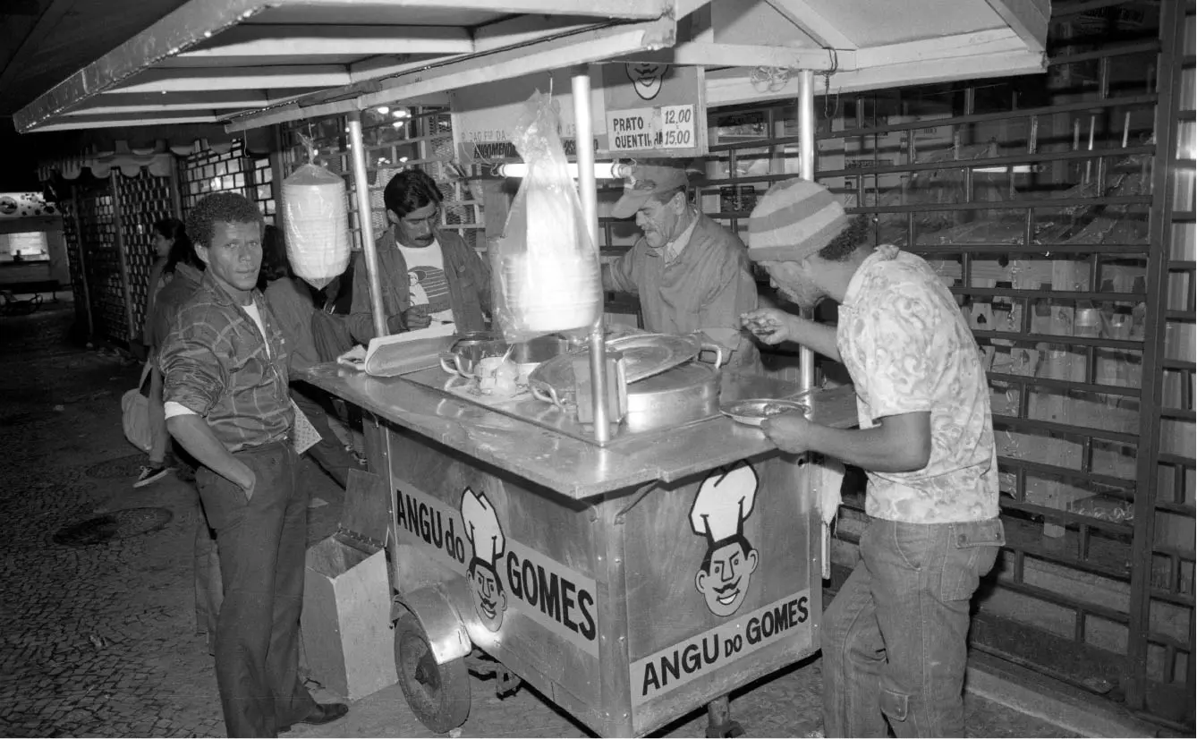 Vendedor ambulante em feira noturna, preparando pratos.