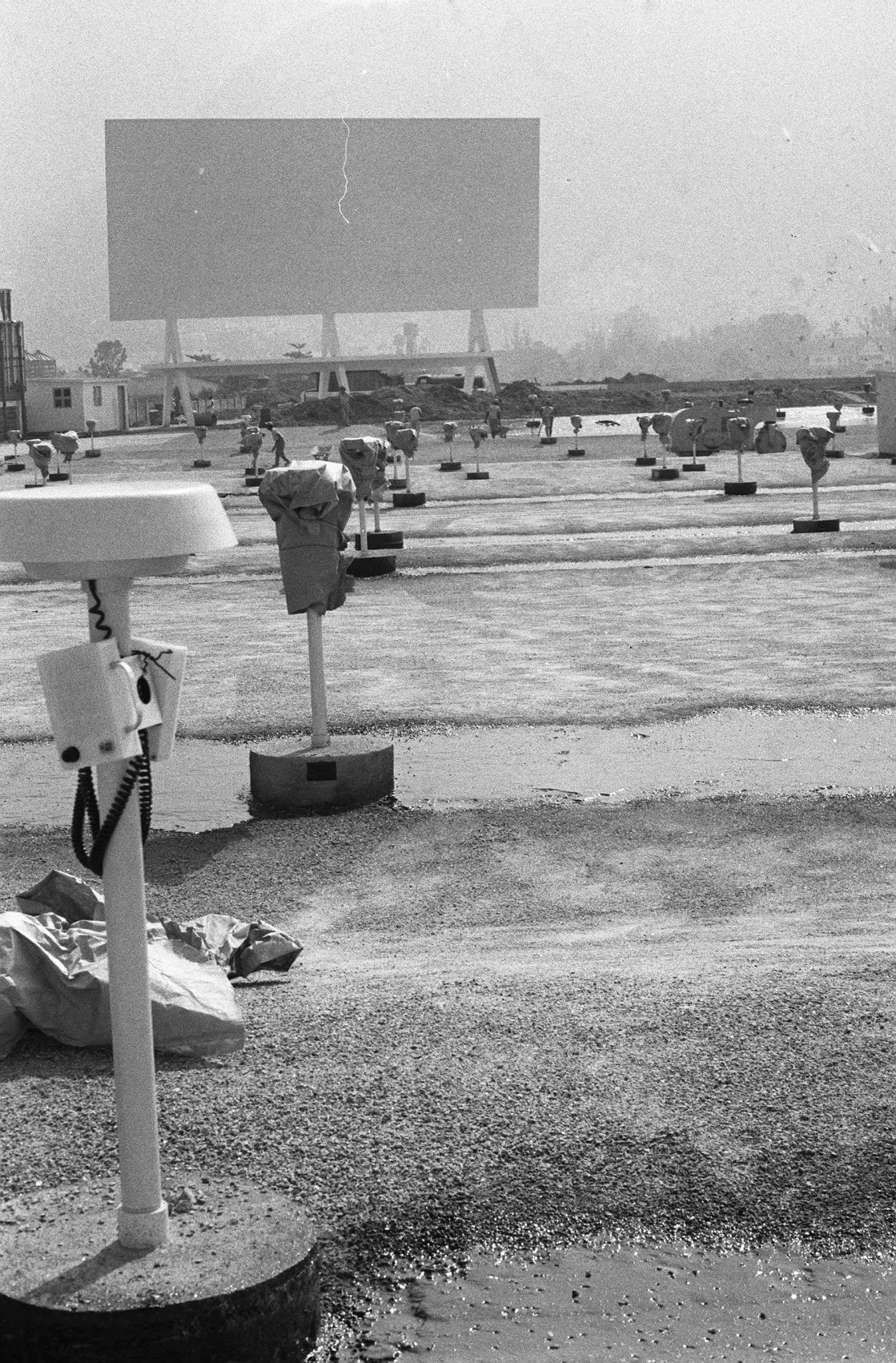 Drive-in em preto e branco com telefone antigo, caixas de som e tela de cinema.