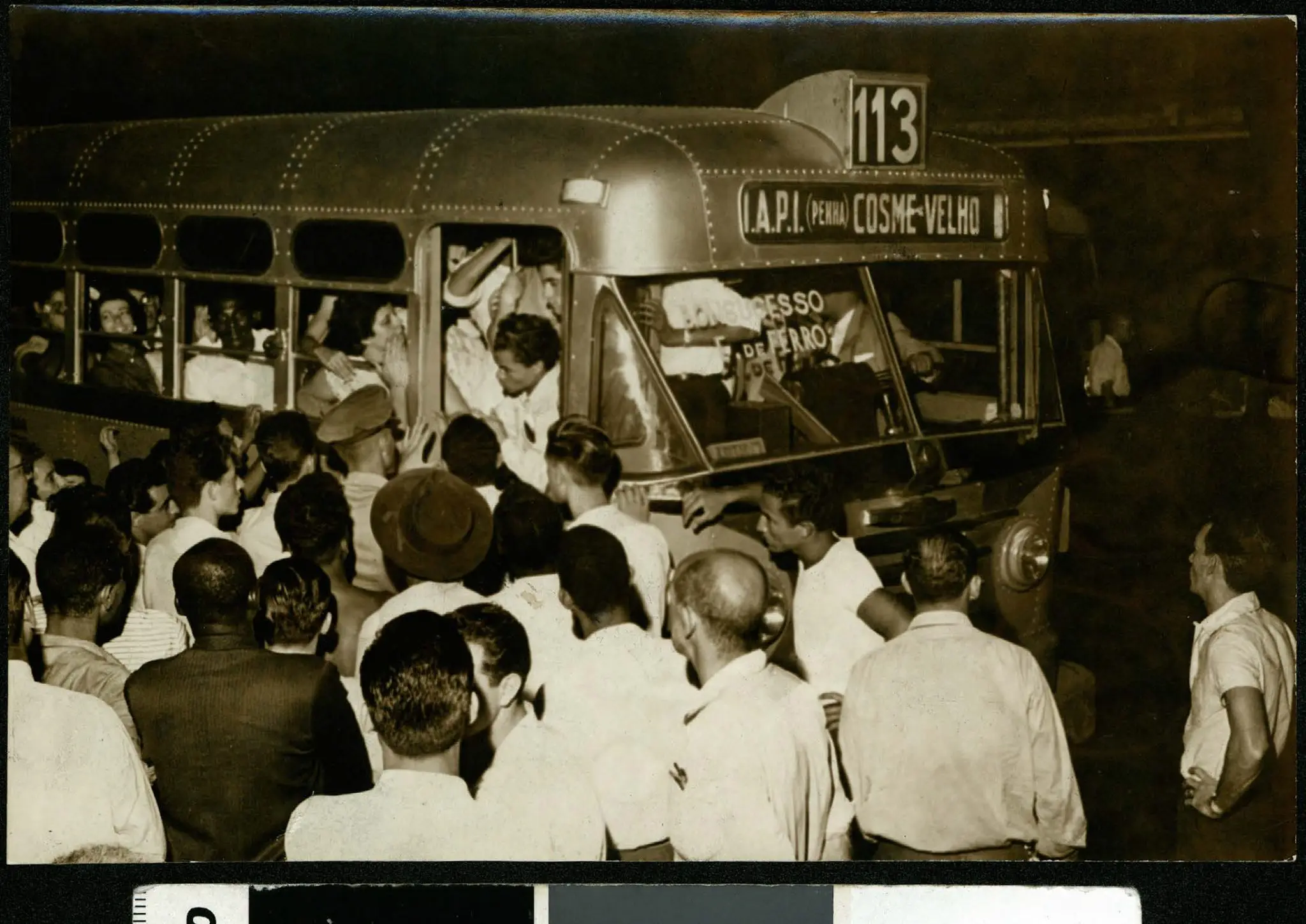Cena urbana preto e branco com pessoas e ônibus.