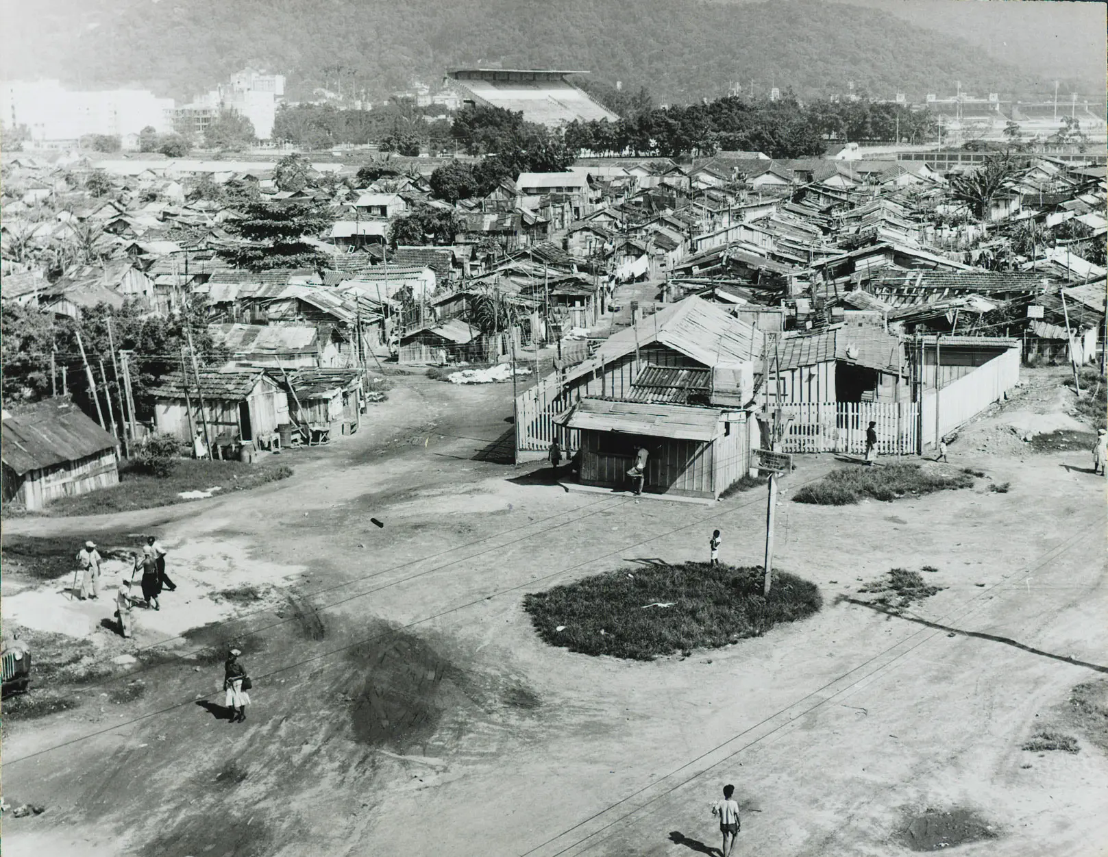 Favela em preto e branco com casinhas de madeira e vegetação.