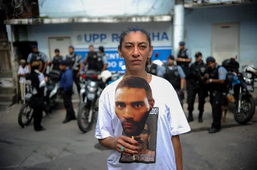 Mulher em frente ao prédio UPP Rio de Janeiro, com camiseta de Amarildo de Souza.