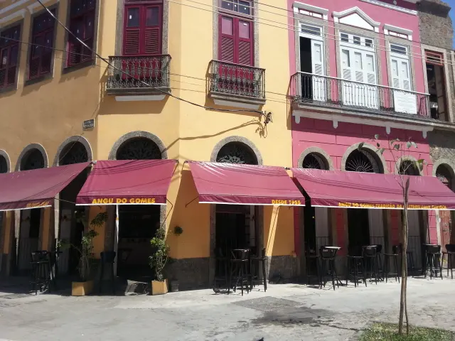 Prédio com fachadas coloridas, mobiliário de bar e plantas verdes.