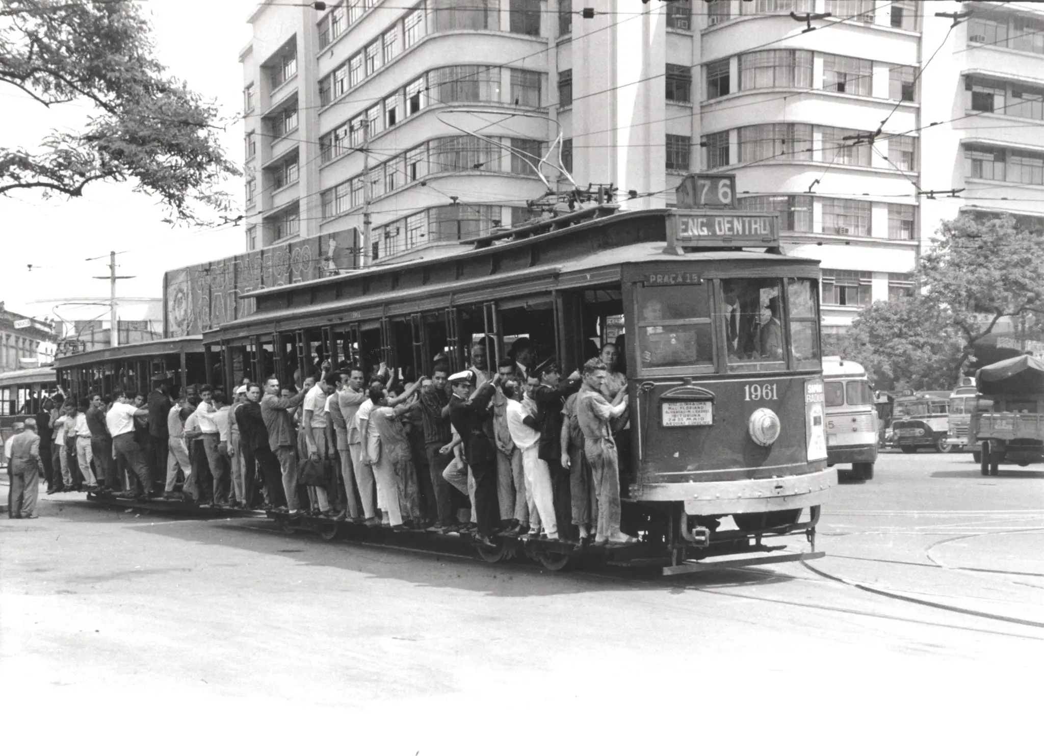 Bonde lotado preto e branco em rua urbana.