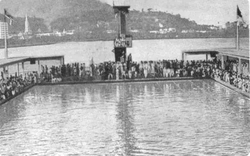 Cerimônia de inauguração de piscina olímpica com multidão e bandeiras.