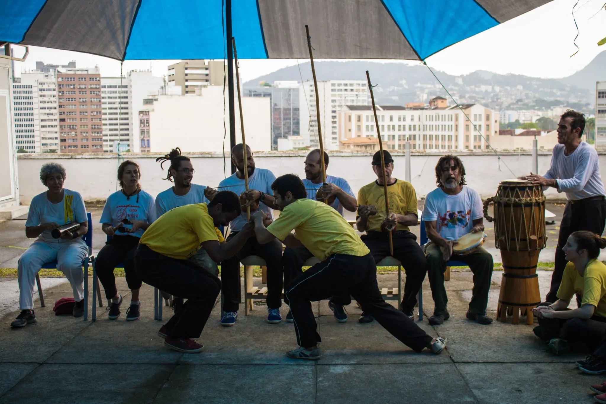 Grupo reunido em local coberto, capoeira e música ao fundo.