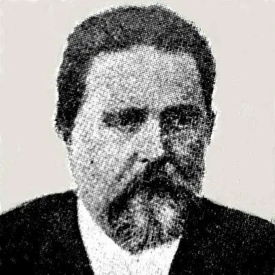 Homem com barba e terno escuro em foto preto e branco desfocada.