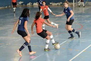 Jogadoras de futsal feminino em campo azul claro.