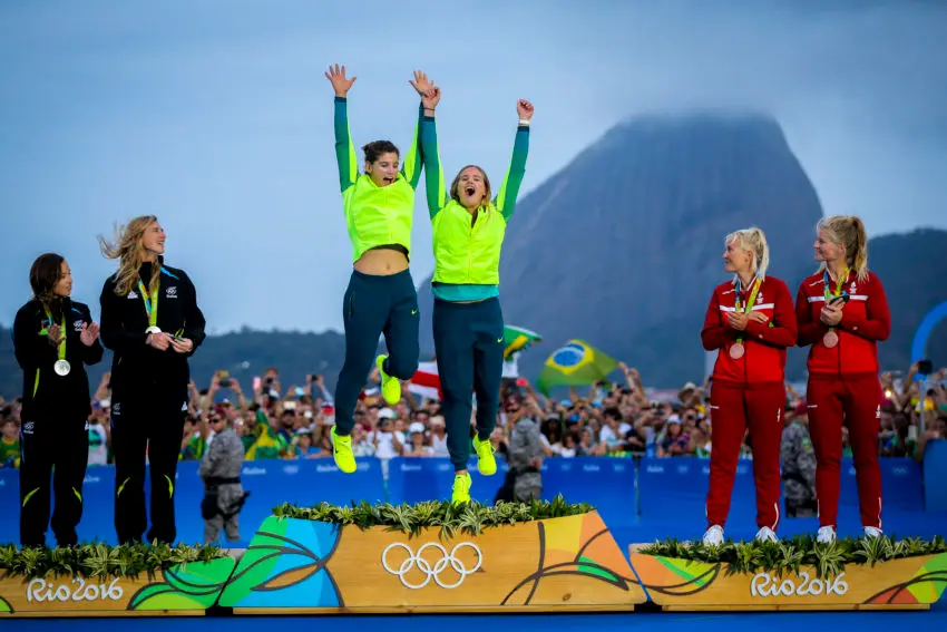 Pódio olímpico com atletas exibindo medalhas e uniformes coloridos.