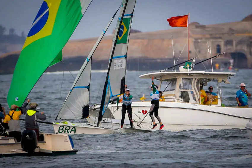 Competição de vela olímpica com velejadores brasileiros celebrando.