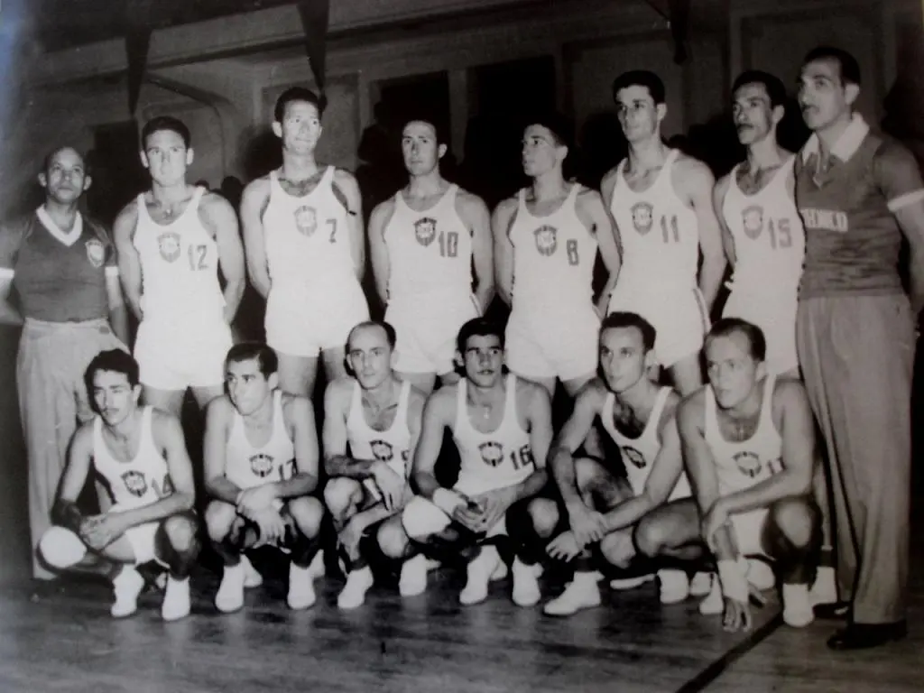 Equipe masculina de vôlei em preto e branco, disposta em duas fileiras.