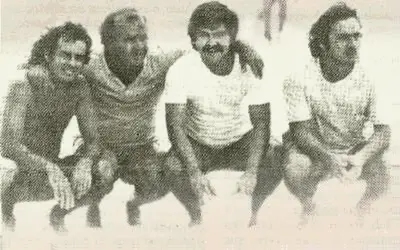 Quatro homens sorridentes em preto e branco.