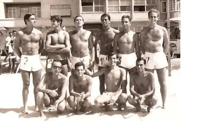 Grupo de homens em praia, preto e branco.