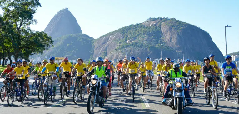 Ciclistas em procissão em estrada, céu azul claro.