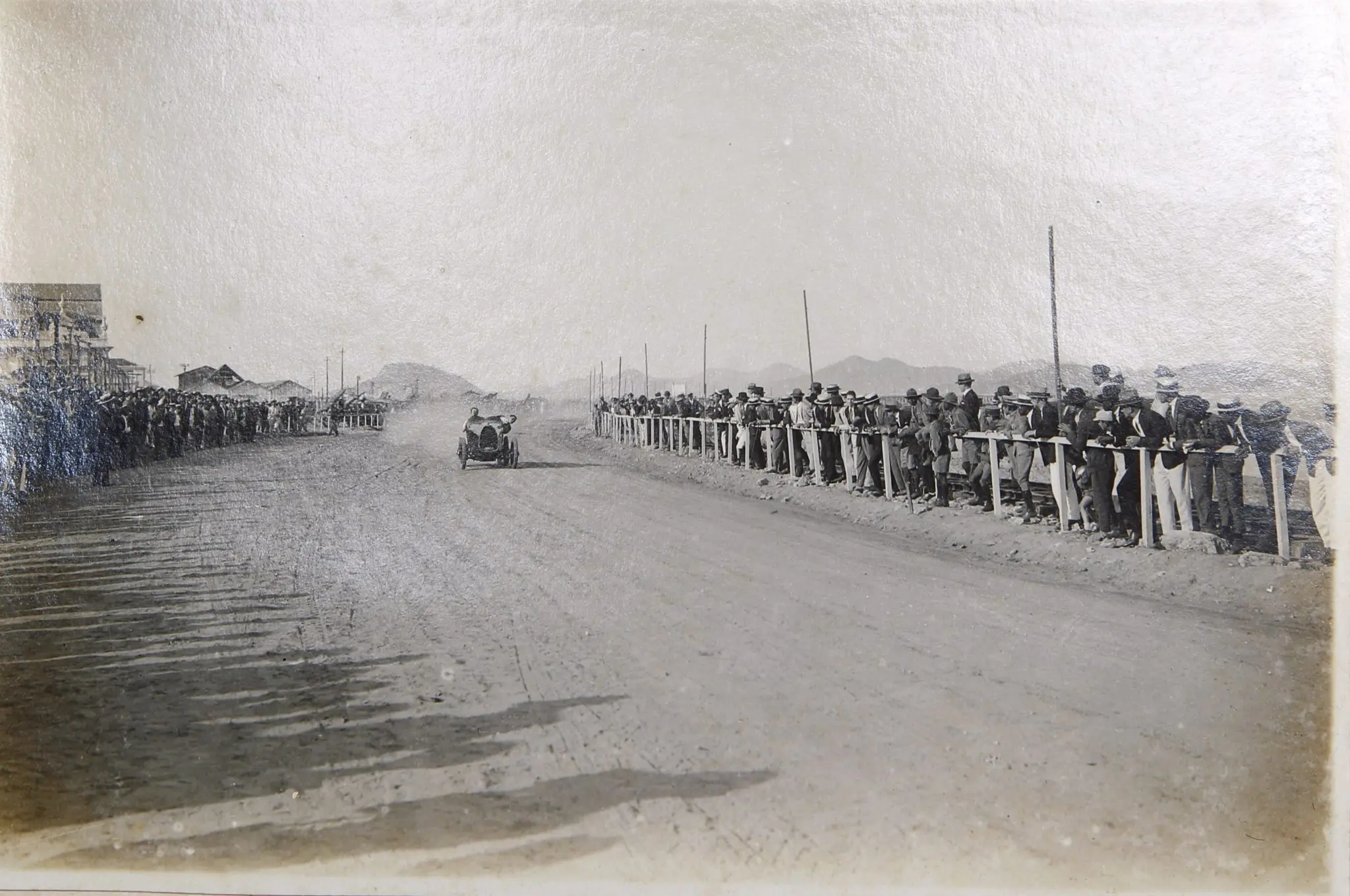 Corrida automobilística em 1925, com público assistindo.