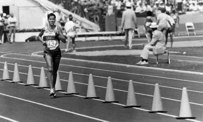 Corredor em movimento durante corrida em estádio.