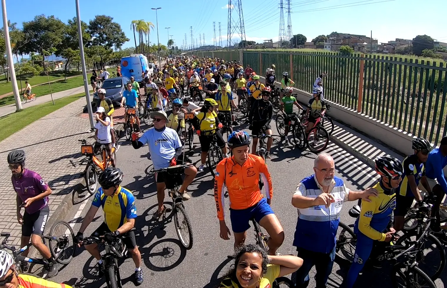 Grande grupo de ciclistas em pista de ciclismo, dia ensolarado.