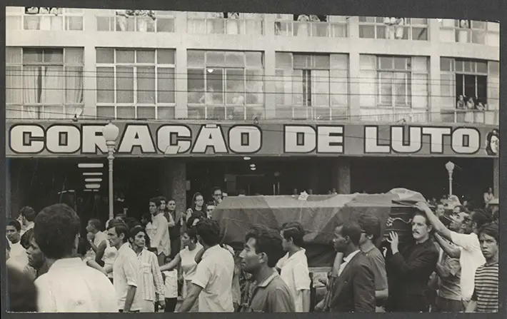 Funeral em preto e branco com multidão e caixão.