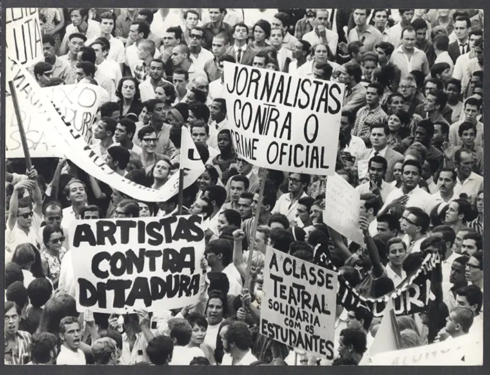 Manifestação pública com cartazes em português.