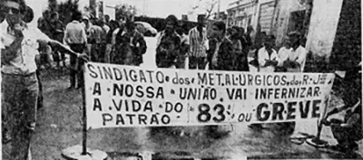 Protesto em preto e branco com faixa e silhuetas de manifestantes.