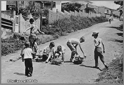 Crianças brincando com carrinho de Rolimã em preto e branco.