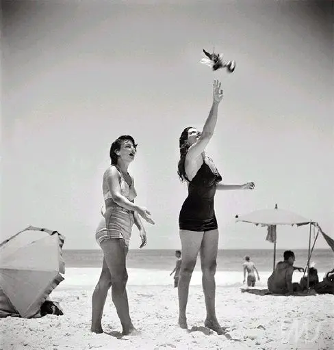 Duas mulheres jogando peteca na praia.