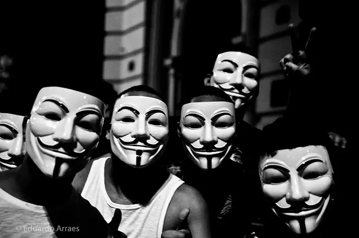 Cinco pessoas com máscaras de Guy Fawkes em uma foto preto e branco.