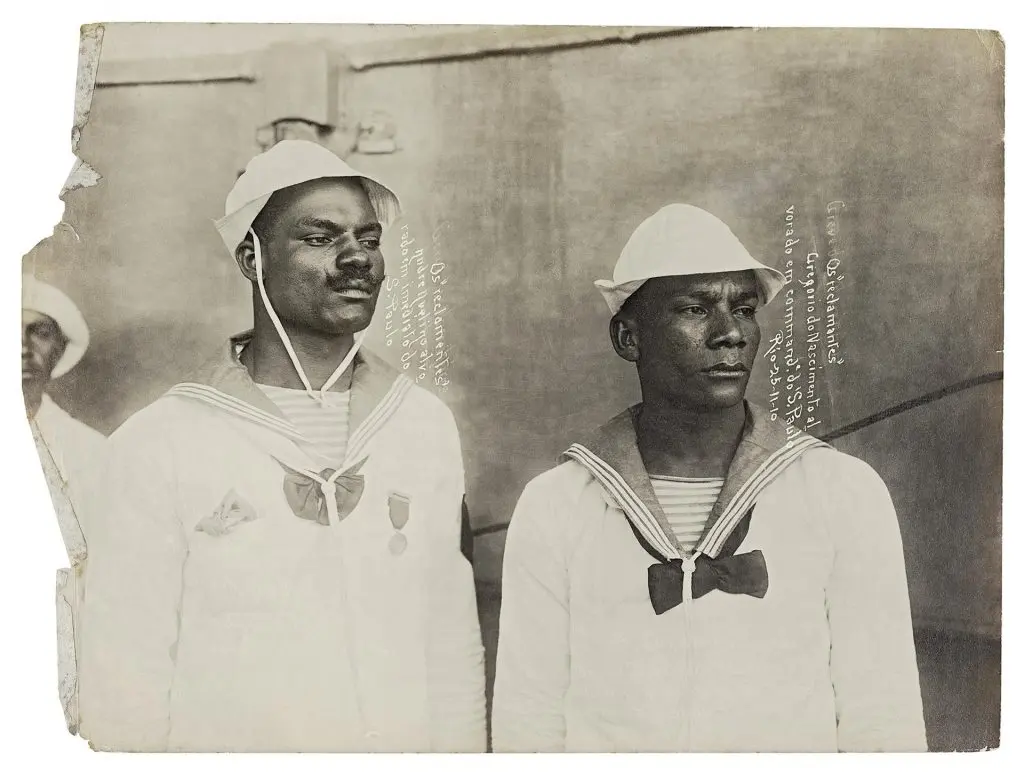 Dois marinheiros em uniforme, chapéu e medalhas, em preto e branco.