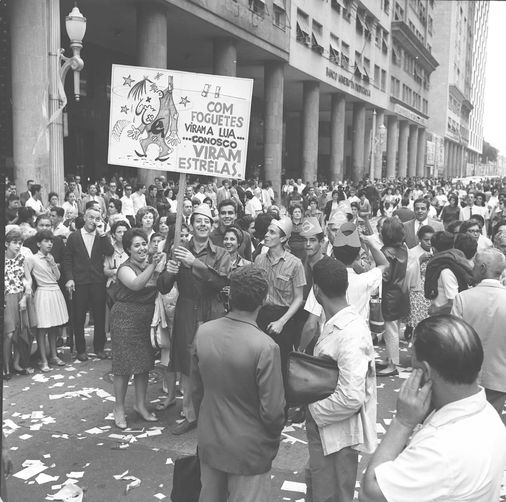 Manifestação pública em preto e branco, multidão em frente a edifício grande.