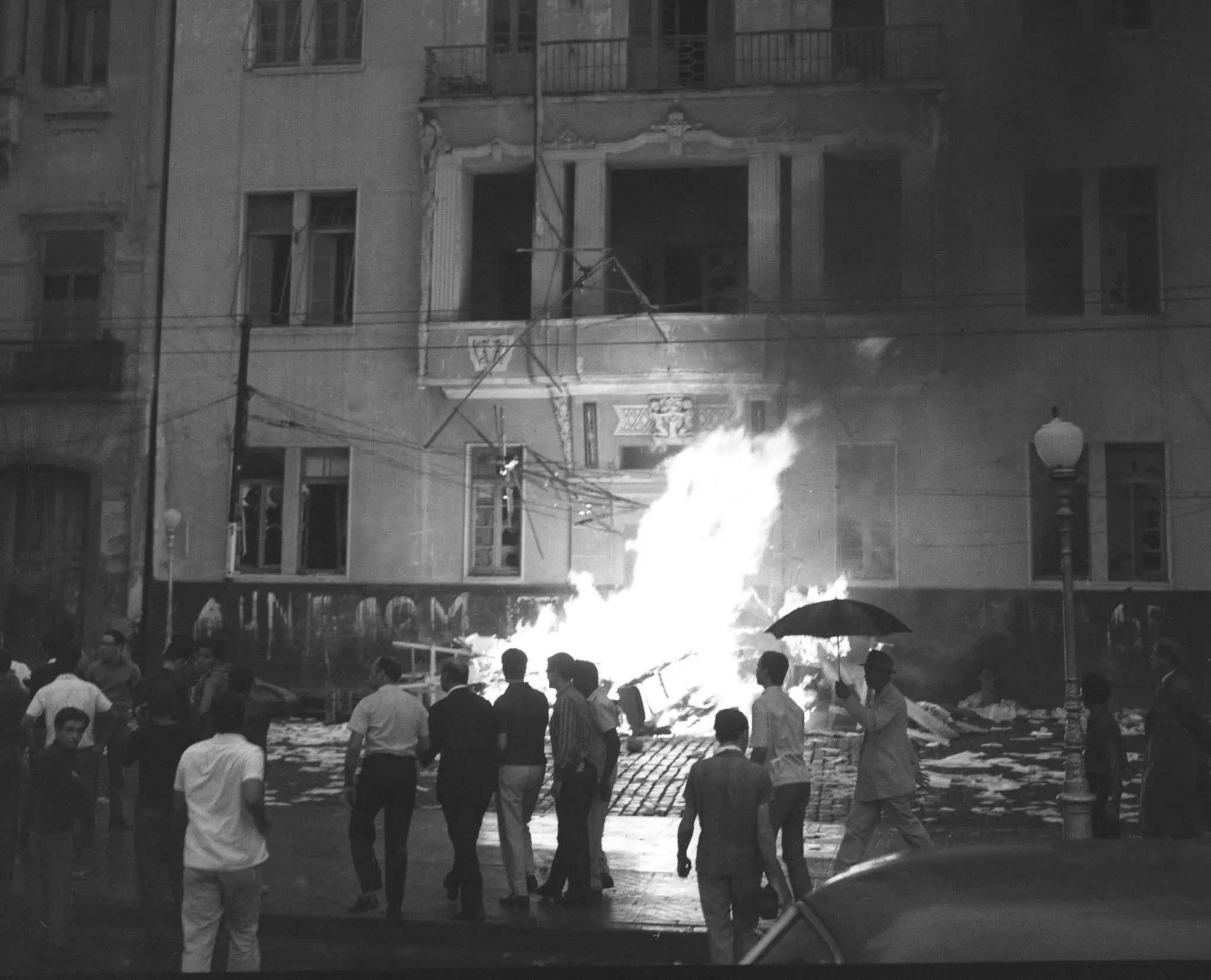Evento violento com incêndio e pessoas observando.