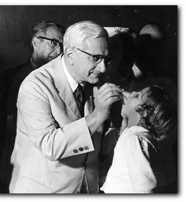 Cena médica em preto e branco com médico examinando criança.